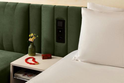 a bed with a pillow and a vase with flowers on a table at Salitre Hotel, Sonder by Marriott Bonvoy in Málaga