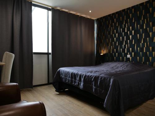 a black bedroom with a bed and a window at Hotel de la Gare in Saint-Mihiel