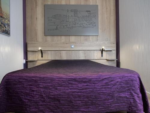 a bed with a purple comforter in a bedroom at Hotel de la Gare in Saint-Mihiel