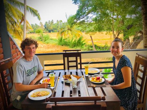 a man and a woman sitting at a table with food at Tranquil Sanctuary Yala in Tissamaharama