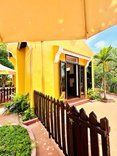 a yellow house with a wooden fence in front of it at Laa House in Hoi An