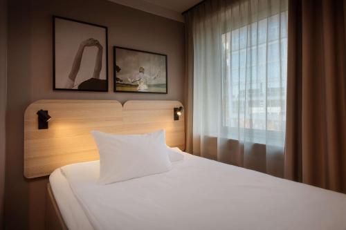 a bedroom with a white bed and a window at Scandic Park Sandefjord in Sandefjord