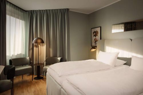 a hotel room with a white bed and a chair at Scandic Park Sandefjord in Sandefjord