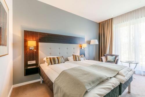a hotel room with a large bed and a chair at Scandic Park Sandefjord in Sandefjord