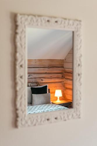 a mirror reflecting a bedroom with a bed and a lamp at CHATA POD PRZEHYBĄ in Stary Sącz