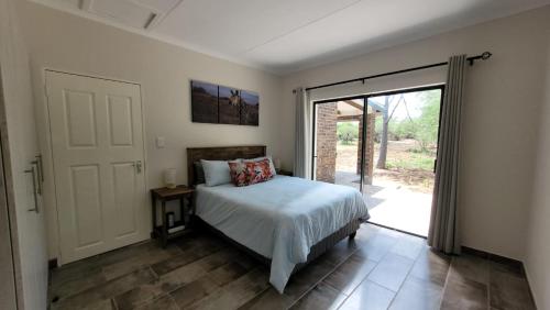 a bedroom with a bed and a sliding glass door at Vachellia View in Marloth Park