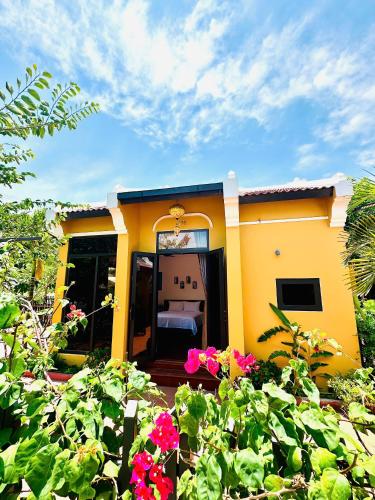 a yellow house with a bed and some flowers at Laa House in Hoi An