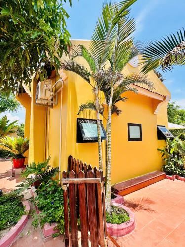 a yellow house with a fence and a palm tree at Laa House in Hoi An