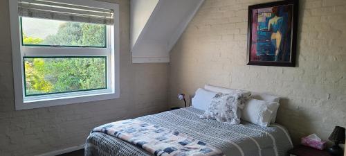 - une chambre avec un lit avec des oreillers et 2 fenêtres dans l'établissement Hout Bay Sea View, au Cap