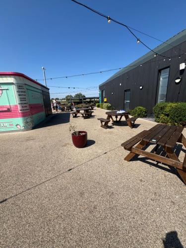a group of picnic tables in front of a building at Singh&Leite Family caravan for 10 people with 2toilets and lovely Decking in Jaywick Sands