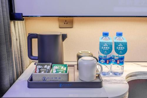 a table with a coffee maker and bottles of water at Dongguan Fenggang Weiduo Hotel in Tiantangwei