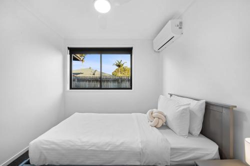 a white bedroom with a bed and a window at Little Mountain Modern Acreage Retreat in Caloundra West