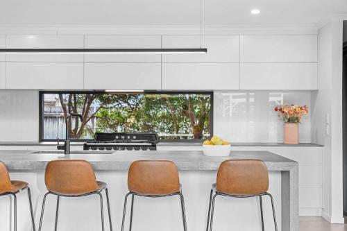 a kitchen with a counter with four chairs at Little Mountain Modern Acreage Retreat in Caloundra West