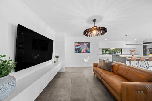 a living room with a couch and a large tv at Little Mountain Modern Acreage Retreat in Caloundra West