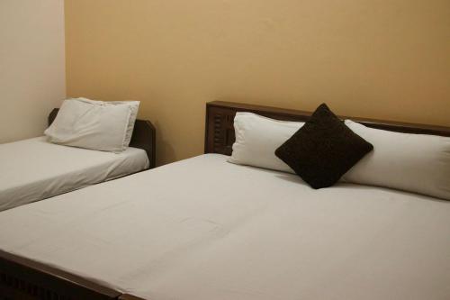 two beds with white sheets and a black pillow at Hotel Krishna in Jaipur