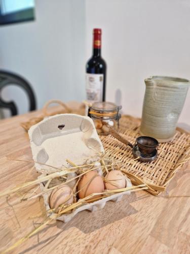 a table with eggs and a bottle of wine at Gîte VITAL Rivière - Charming cottage in Peyrus