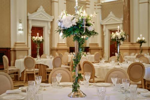a banquet hall with tables with white flowers and candles at The College Green Dublin Hotel, Autograph Collection in Dublin