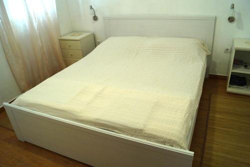 a bed in a bedroom with a white bedsheet at Apartments Kuća Grško in Selce