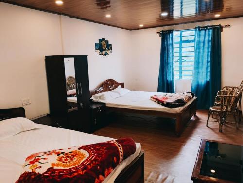 ダージリンにあるMountain Paradise Homestay BATASIA LOOPのベッドが2つとテレビがある部屋