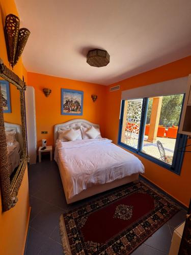 a bedroom with orange walls and a bed and a mirror at Dar NFis Suites et chambres de luxe dans un havre de paix vue paradisiaque au bord du lac in Lalla Takerkoust