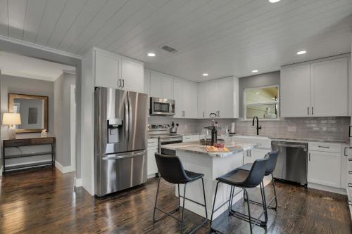 a kitchen with white cabinets and a kitchen island with chairs at Upscale Home with Pool and FirePit - Close to Mercer St! in Dripping Springs