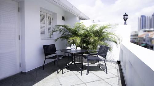 a table and chairs on a balcony with a plant at Hotel Calmo Hamilton in Singapore