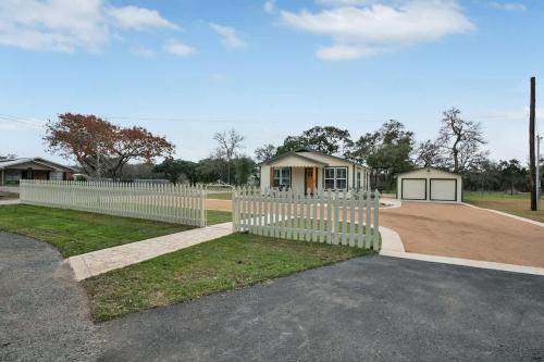 a white picket fence in front of a house at Upscale Home with Pool and FirePit - Close to Mercer St! in Dripping Springs