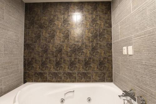 a bath tub in a bathroom with a tile wall at 캠프관광호텔 in Seoul