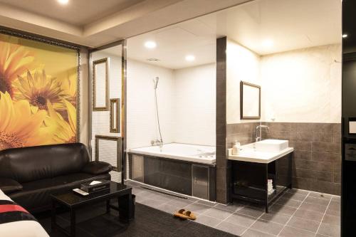 a bathroom with a tub and a sink and a couch at 캠프관광호텔 in Seoul