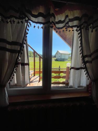 a window with curtains and a view of a yard at Садиба Урочище Луг in Vorokhta