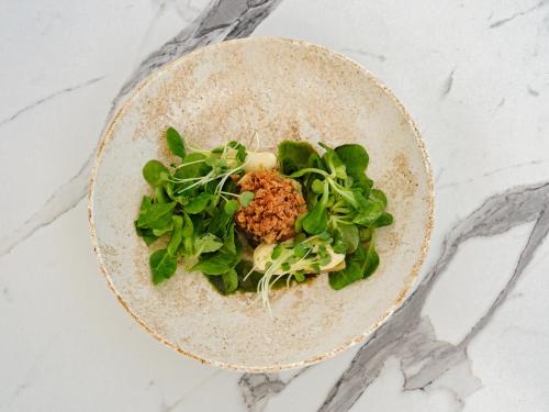 a plate of food with greens on a table at Aegean Melathron Thalasso Spa Hotel in Kallithea Halkidikis