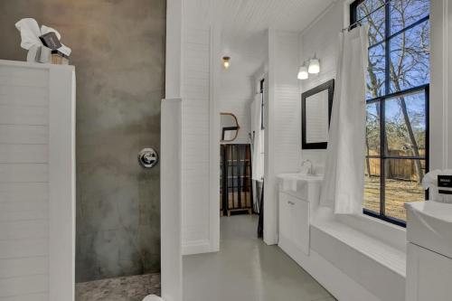 ein weißes Badezimmer mit Dusche und Waschbecken in der Unterkunft Gorgeous Home 1 Blk from Main with Hot Tub & Fire Pit! in Fredericksburg