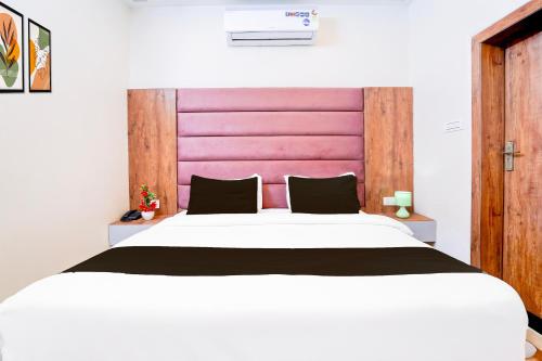 a bedroom with a large white bed with a pink headboard at Townhouse Govardhan in Govardhan