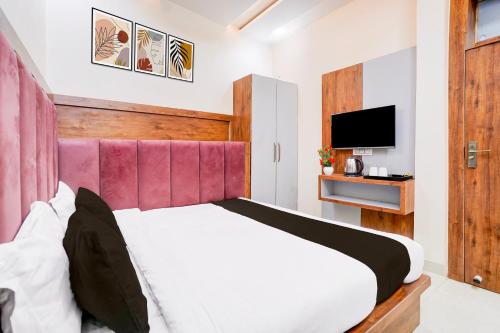 a bedroom with a bed with a pink headboard and a television at Townhouse Govardhan in Govardhan
