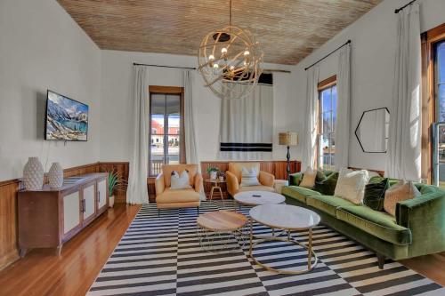 ein Wohnzimmer mit einem grünen Sofa und einem Kronleuchter in der Unterkunft Gorgeous Home 1 Blk from Main with Hot Tub & Fire Pit! in Fredericksburg