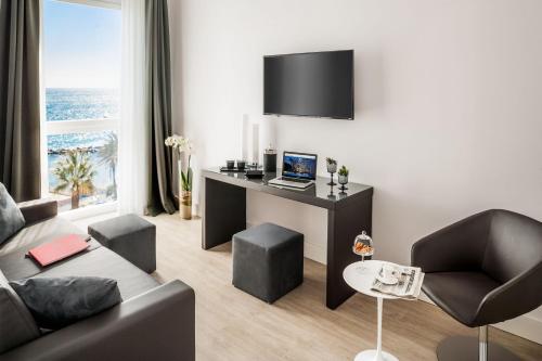a living room with a couch and a desk with a laptop at Miramare The Palace Resort in Sanremo