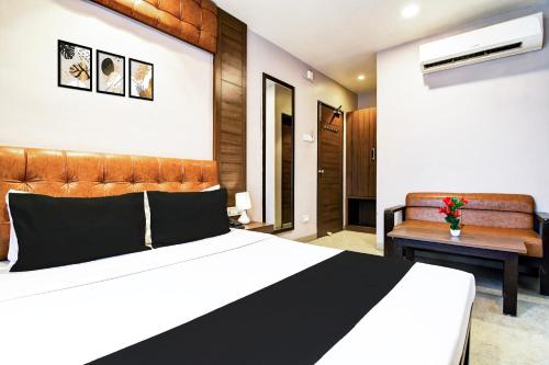 a bedroom with a large bed and a bench at Super Hotel O Tagore Park Laskarhat formerly Shankar Guest House in Kolkata