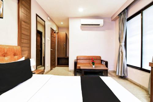 a bedroom with a bed and a chair and a window at Super Hotel O Tagore Park Laskarhat formerly Shankar Guest House in Kolkata