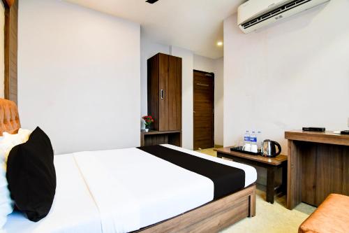 a bedroom with a white bed and a wooden cabinet at Super Hotel O Tagore Park Laskarhat formerly Shankar Guest House in Kolkata