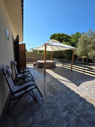 a pair of chairs and an umbrella on a patio at Villa Giacoma hot tub and garden in Mandra Capreria