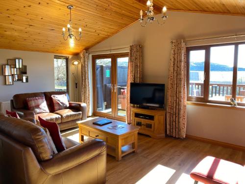 a living room with a couch and a television at Barn Lodge with Hot Tub in Cupar