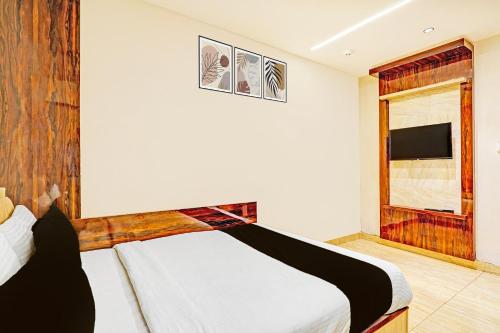 a bedroom with a bed and a tv on the wall at Super Townhouse Indiranagar in Bengaluru