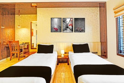 a room with two beds and a table with a desk at Super Townhouse Indiranagar in Bengaluru
