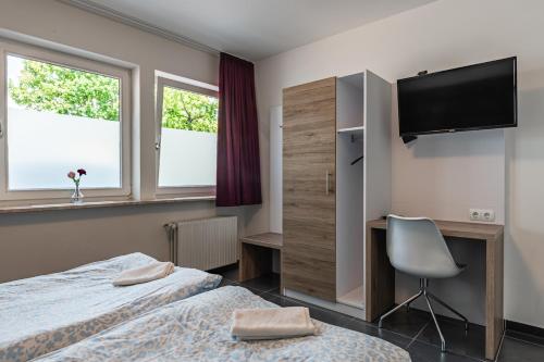 a hotel room with two beds and a desk and a television at MK Hostel Oyten - free Wifi & Parking - 24h Check-In in Oyten