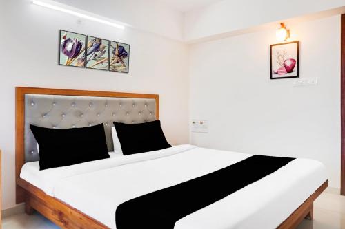 a bedroom with a large white bed with black pillows at Super Townhouse Lohegaon Near Pune Airport formerly Landmark Regency in Pune