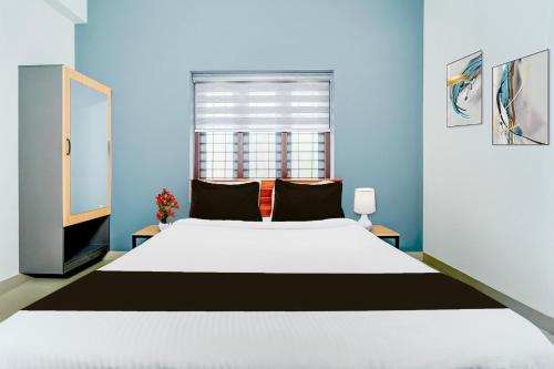a bedroom with a large white bed and a window at Super Hotel O Kazhakootam Near Technopark Phase 2 in Trivandrum