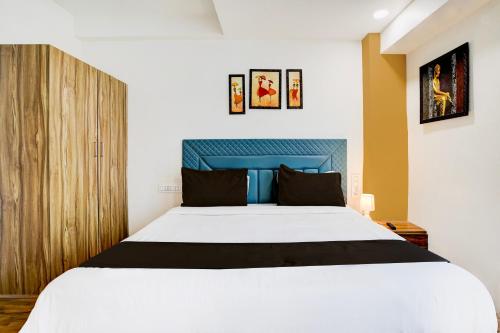 a bedroom with a white bed and a blue headboard at Super Collection O Vesu Surat Formerly Hotel Signature in Surat