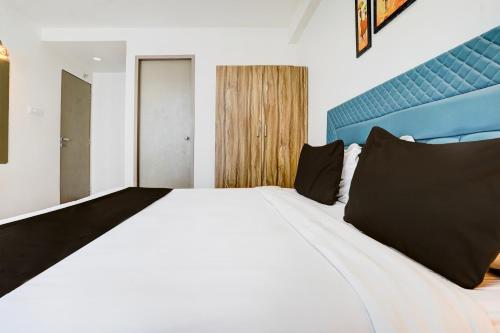 a bedroom with a large white bed with black pillows at Super Collection O Vesu Surat Formerly Hotel Signature in Surat