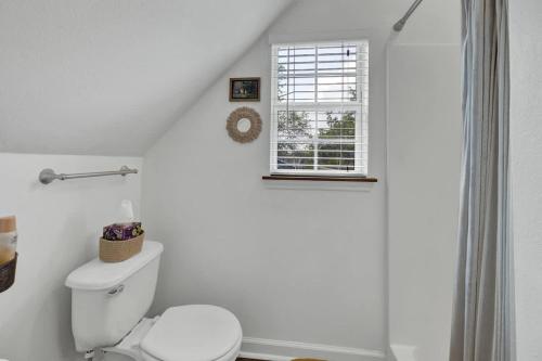 a white bathroom with a toilet and a window at Cactus Flower Treehouse-Pet Friendly-Hill Country Views! in Luckenbach
