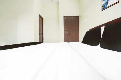 a bedroom with two large white beds and a door at Super Hotel O Rajendra Nagar Hingna Road in Nagpur